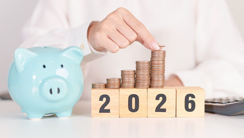 previdenza-cooperativa-immagine-news Una persona compone il numero 2026 con cubi di legno e pile di monete crescenti accanto a un salvadanaio, rappresentando il TFR e le nuove soglie dimensionali 2026.