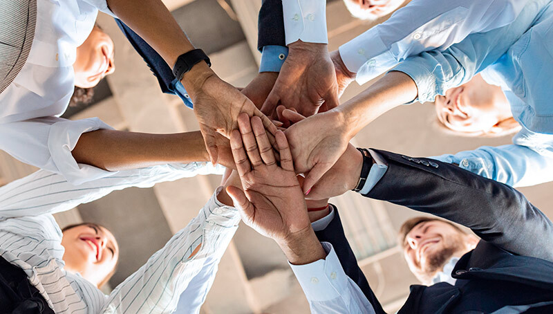 Team di professionisti disposti in cerchio che uniscono le mani al centro come simbolo di collaborazione e governance trasparente.