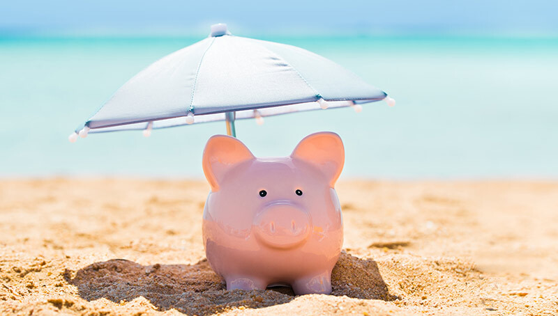 Salvadanaio sotto un ombrellone sulla spiaggia, immagine sul tema del risparmio e del fondo pensione